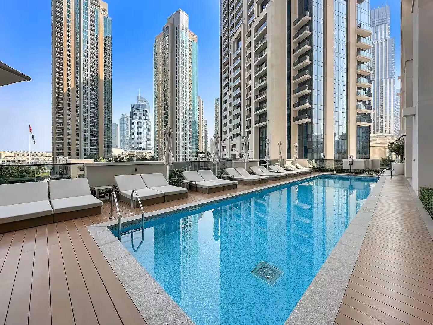 Un espace piscine aménagé sur le toit, avec des chaises longues et une vue sur les immeubles environnants.
