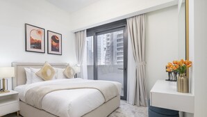 Un dormitorio moderno con una cama grande, una mesita de noche, un tocador y una ventana con cortinas.