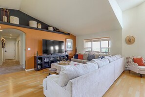 A spacious living room with a large sectional sofa, a flat-screen TV, and a wooden floor. - Luxe Mesa View Home on 35 Acres w/ Wraparound Deck (Glade Park)