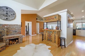 Un vaste espace de vie agrémenté d’une cheminée en pierre, d’un meuble en bois orné de sculptures décoratives et d’un grand tapis.