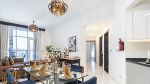 Uma área de jantar moderna com mesa de vidro, cadeiras estofadas azuis e um candelabro.