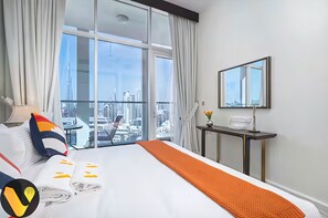 Ein Hotelzimmer mit einem großen Bett, einem Schreibtisch, einem Spiegel und Blick auf die Stadt.