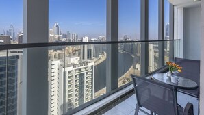 Uma varanda com vista desimpedida para o horizonte urbano, uma mesa com cadeiras e um vaso com flores.
