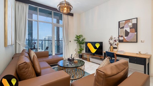 Uma sala de estar moderna com um sofá, uma mesa de centro de vidro, uma TV e uma escrivaninha.