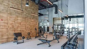 Ein modernes Fitnessstudio mit unterschiedlichen Trainingsgeräten, großen Fenstern und einer Wand mit Holzverkleidung.