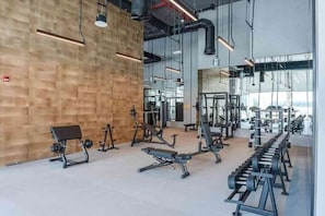 Un gimnasio moderno con diverso equipo de ejercicio, amplias ventanas y un revestimiento de pared de madera.