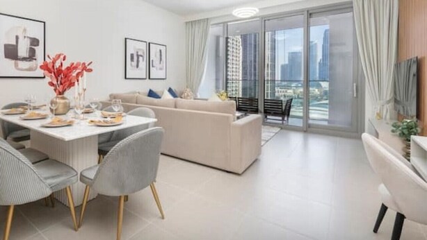 Ein modernes Wohnzimmer mit Essbereich, einer Couch und einem Balkon mit Blick auf die Stadt.