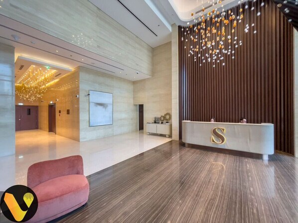 A modern reception area with a reception desk, a plush seating area, and a decorative light fixture.