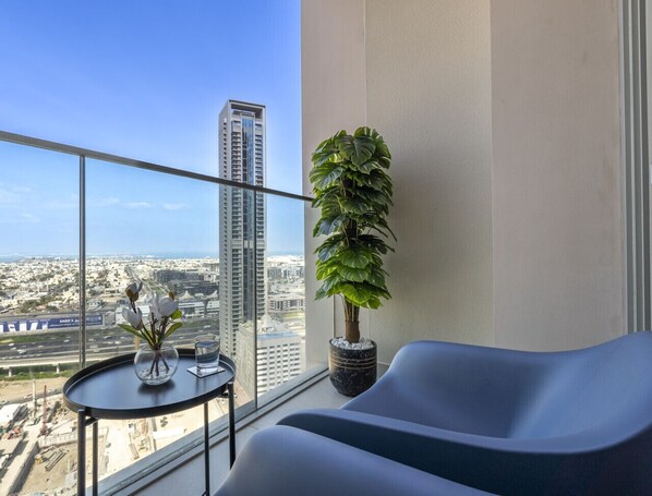 A balcony with a view of a cityscape, a potted plant, and a seating area with a table.