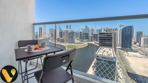 A balcony with a city view, a table with chairs, and a pair of mugs.