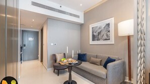 Ein modernes Wohnzimmer mit einem grauen Sofa, einem kleinen runden Tisch mit Kerzen und einem gerahmten Kunstwerk an der Wand.