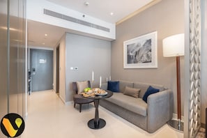 A modern living room with a grey sofa, a small round table with candles, and a framed artwork on the wall.