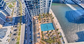 A high-rise hotel with a rooftop pool, a marina, and a road with vehicles. - Vogue, DAMAC Maison Privé near Dubai Mall and Burj Khalifa (Dubai)