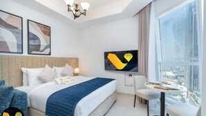 Ein modernes Hotelzimmer mit einem großen Bett, einem Fernseher, einem Esstisch und Blick auf die Stadt.