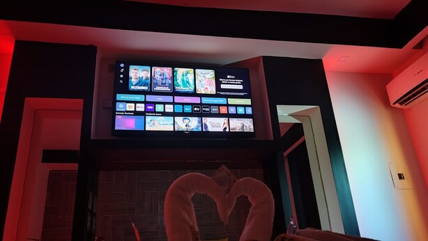 A hotel room with a TV displaying various channels and a heart-shaped towel arrangement on the bed. - AUTO HOTEL CONSTELACION  (Nacajuca)