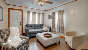 A living room with a ceiling fan, a grey sofa, a patterned armchair, a beige armchair, and a wooden coffee table. - Aunt Lele's Cozy Cottage (Quincy)