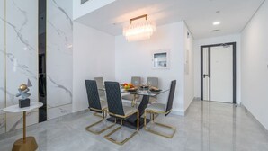 Un comedor moderno con pared de mármol, una araña y una mesa dispuesta para cuatro.