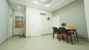 A room with a dining table and chairs, a door, a small plant, and a painting on the wall.