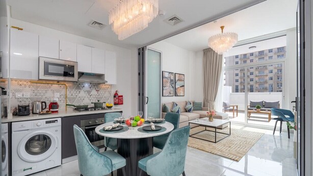 A modern kitchen with a built-in microwave, washing machine, and a dining area with a round table and chairs. - Vogue, Al Furjan Pearlz by Danube near Ibn Battuta Mall (Dubai)