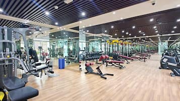 A gym with various exercise equipment, mirrored walls, and a wooden floor.