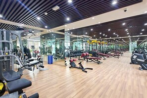 Ein Fitnessraum mit unterschiedlichen Trainingsgeräten, Spiegelwänden und einem Holzboden.