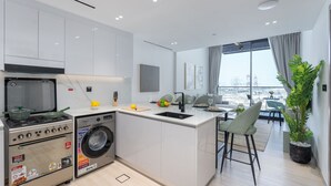 Una cocina moderna con horno integrado, microondas y lavadora, un comedor con vistas y una planta grande en maceta.