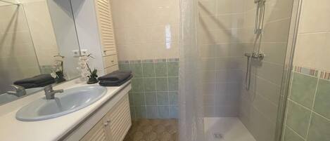 A bathroom with a shower, sink, and mirror.