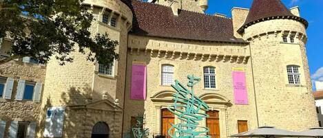 A historic stone building with a central courtyard, a prominent tower, and a decorative metal sculpture.