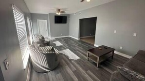 A spacious living room with a large sectional sofa, a coffee table, and a ceiling fan.
