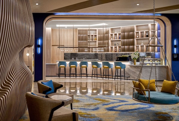 A modern interior with a bar area, seating with cushions, and a hanging swing. - voco Bandung Setiabudi by IHG (Bandung)