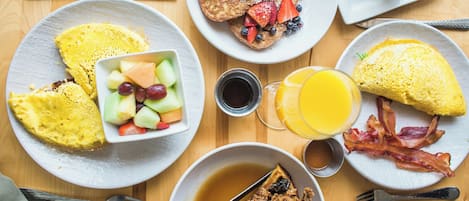 A breakfast table with various dishes including waffles, eggs, and fruit.