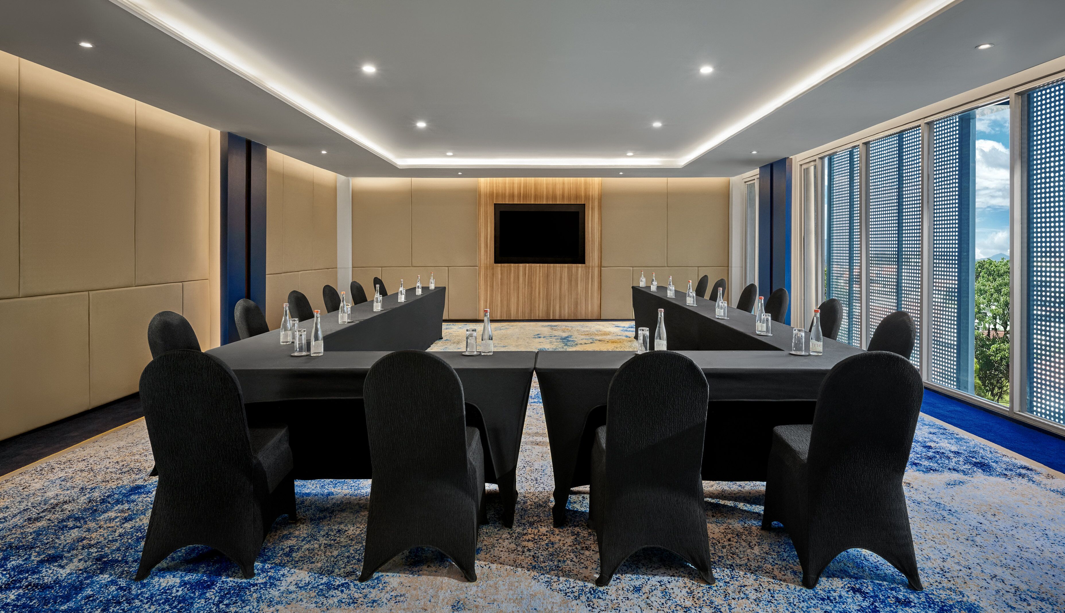 A conference room with a long table, chairs, and a TV screen.