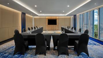 A conference room with a long table, chairs, and a TV screen.