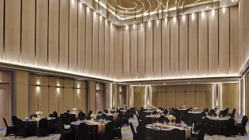 A large conference room with multiple round tables, black chairs, and a patterned carpet.
