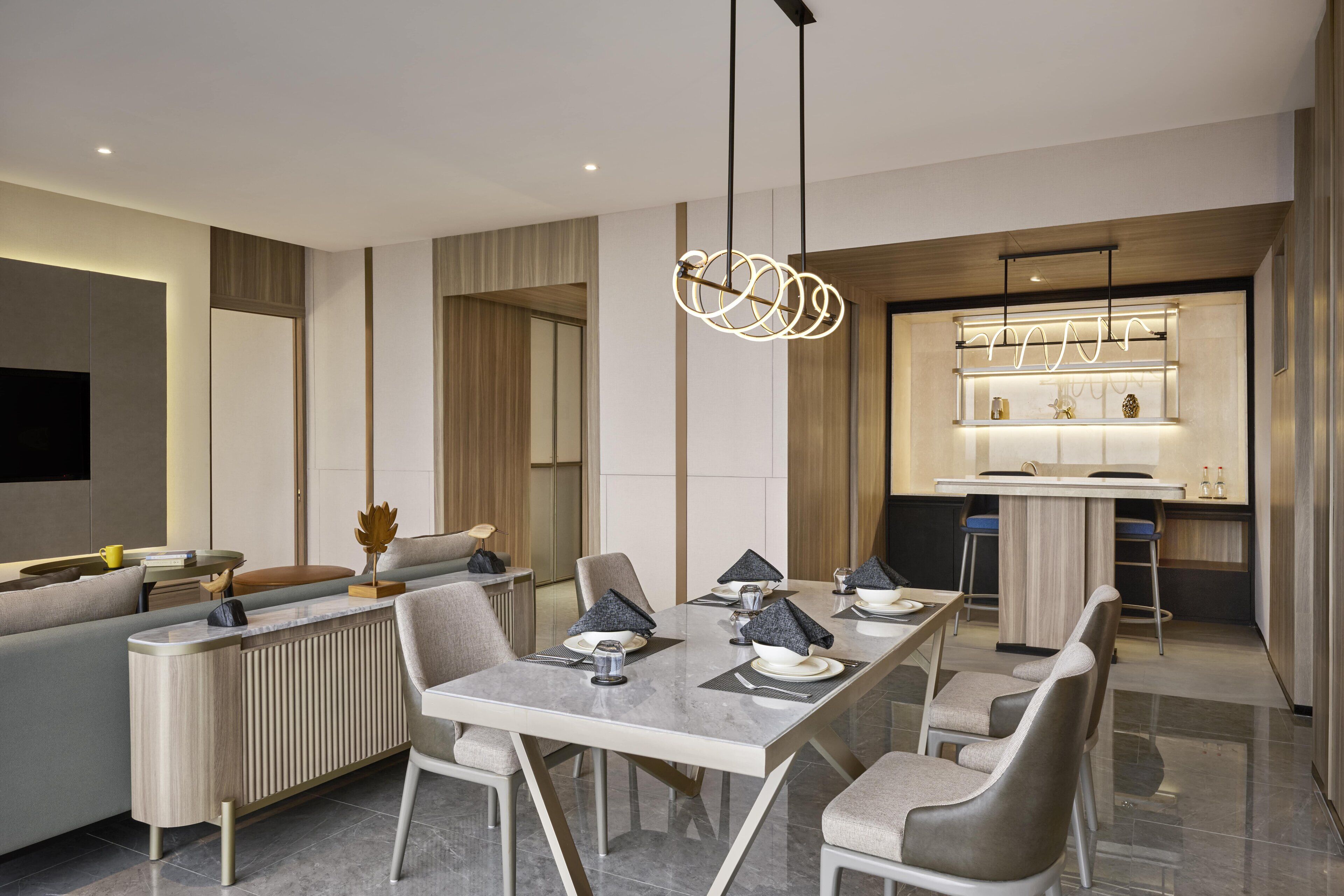 A modern dining area with a marble table, grey upholstered chairs, and a contemporary pendant light.