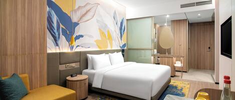 Una habitación de hotel moderna con una cama, un sofá, una mesita y un espejo.