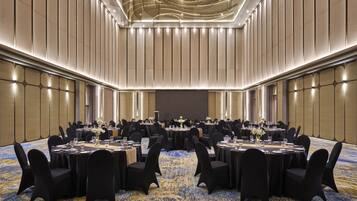 Une grande salle de conférence avec des tables rondes, des chaises noires et un tapis à motifs.
