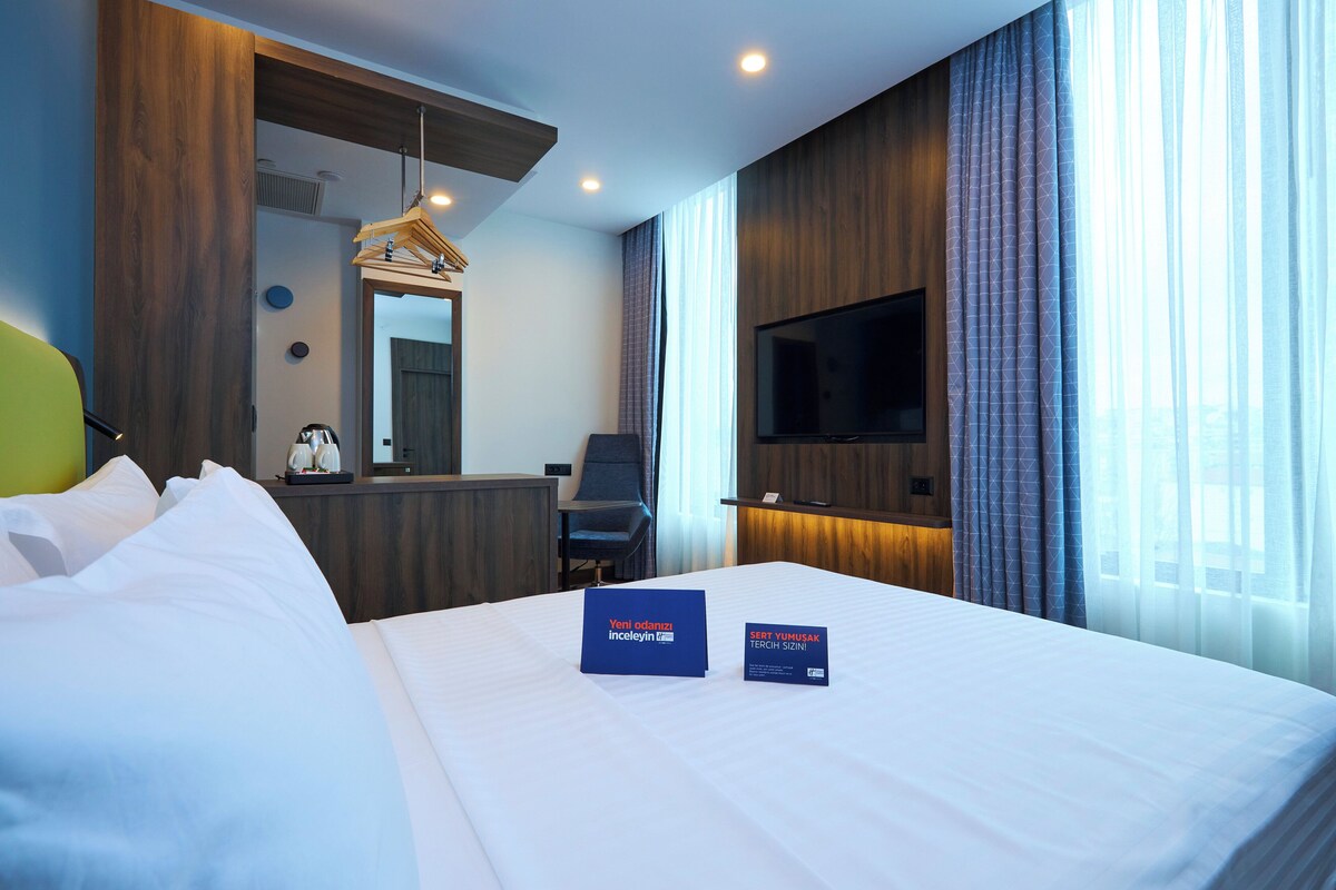 A hotel room with a bed, a TV, a desk, and a mirror.