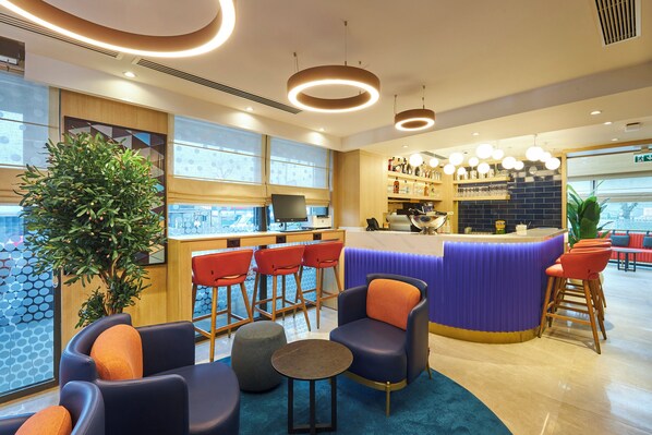 A modern bar area with a counter, seating, and a large plant. - Holiday Inn Express Istanbul - Airport Arnavutkoy by IHG (Arnavutkoy)