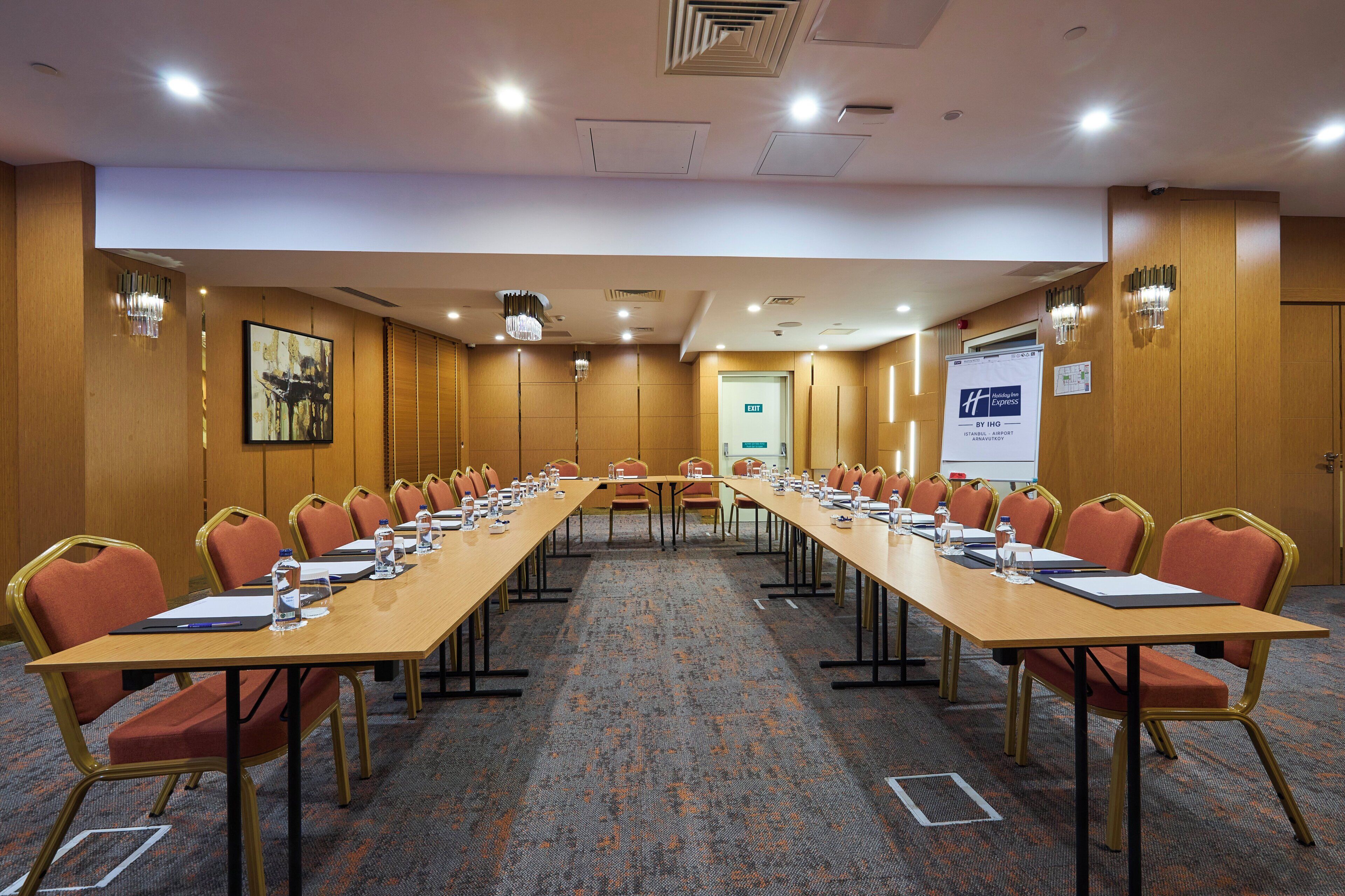 A conference room with a long table, chairs, and a projector screen.