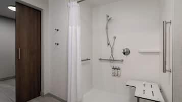 Casa de banho moderna com cabine de duche, lavatório branco e porta de madeira.