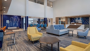A modern lobby with seating areas, a reception desk, and a cityscape mural.