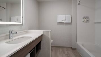 A bathroom with two sinks, a mirror, a toilet, and a bathtub.