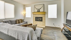 A living room with a fireplace, a sofa, and a television. - Pool Table & Charcoal Grill: Home in Victorville! (Victorville)