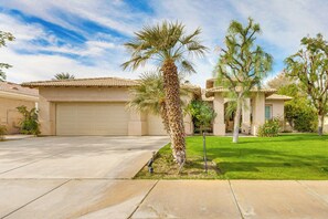 A residential property with a garage, a well-maintained lawn, and mature trees.