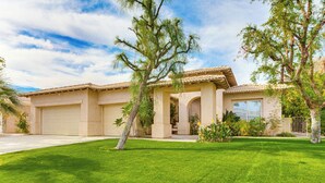 A two-story house with a tiled roof, a front garage, and a well-maintained lawn. - Family Friendly: Spacious Oasis in Palm Desert! (Palm Desert)