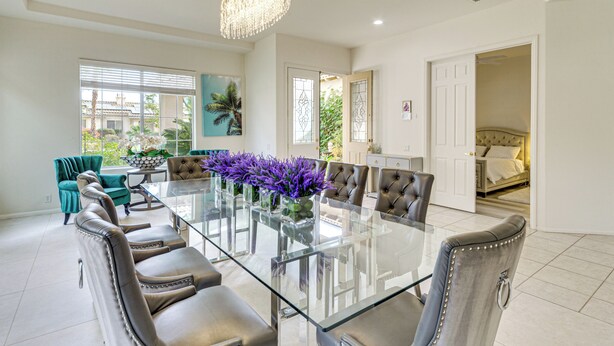 A spacious dining area with a glass table, leather chairs, and a chandelier. - Family Friendly: Spacious Oasis in Palm Desert! (Palm Desert)