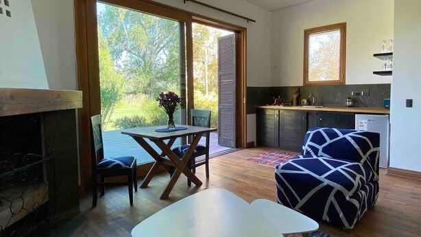 Un salon moderne avec une cheminée, une table à manger et un canapé. Il y a également un coin cuisine avec une fenêtre et un petit îlot.