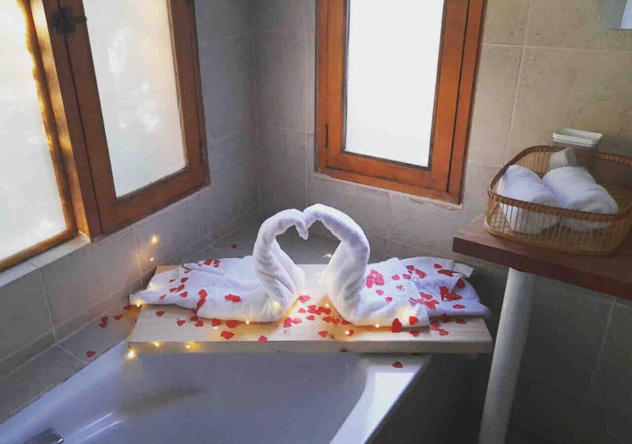 Un bagno con una vasca, due finestre e un cesto di asciugamani su uno scaffale.