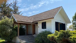 Une maison de plain-pied avec un toit en pente, une véranda et une entrée principale avec des marches.